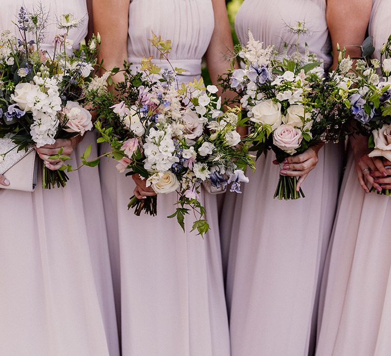 Purple, pink and white flower wedding bouquets held by bridesmaids in blush pink chiffon dresses