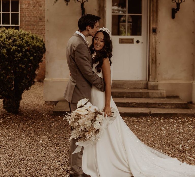 Groom kisses the bride on the forehead as they take their couple portraits together