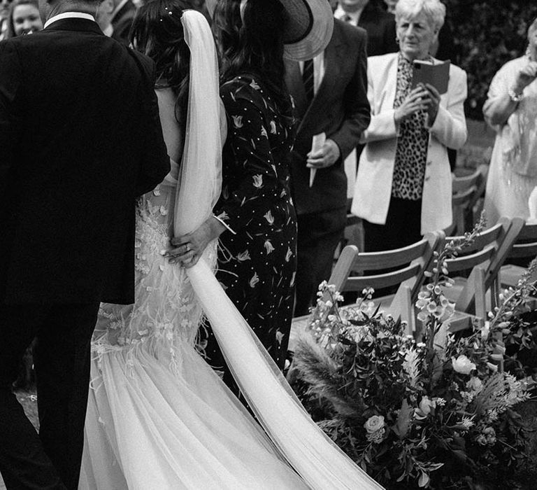 Mother and father of the bride walk the bride down the aisle in her tulle wedding dress 