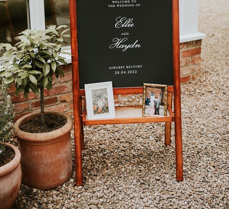 Welcome wedding sign on chalk board complete with photos of bride & groom in frames