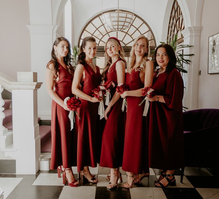 Dark red bridesmaid dresses for the bridal party with matching small red flower bouquets for city wedding 