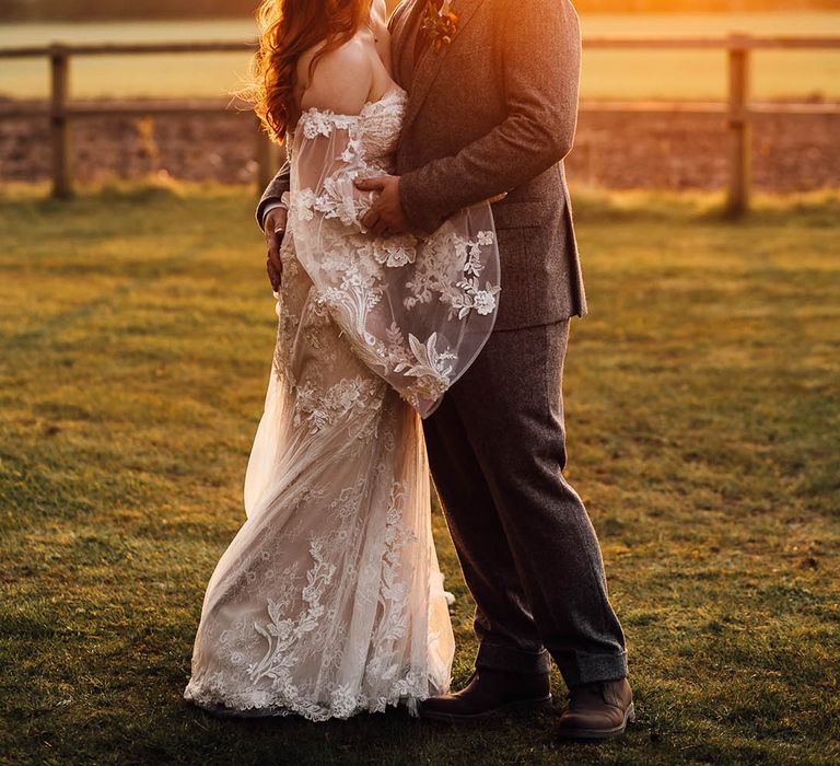 Bride and groom kiss during golden hour 