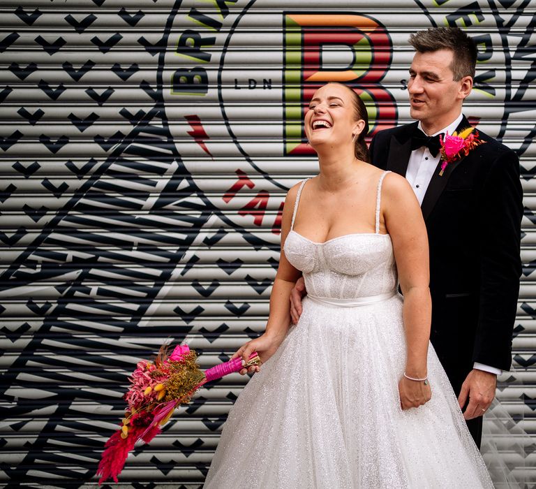 Bride wears fitted sparkly wedding dress with princess skirt and carries bright dried floral bouquet 