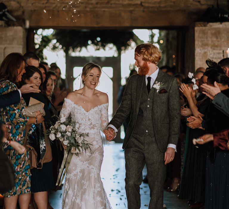 Bride and groom exit from their ceremony to confetti at Stone Barn