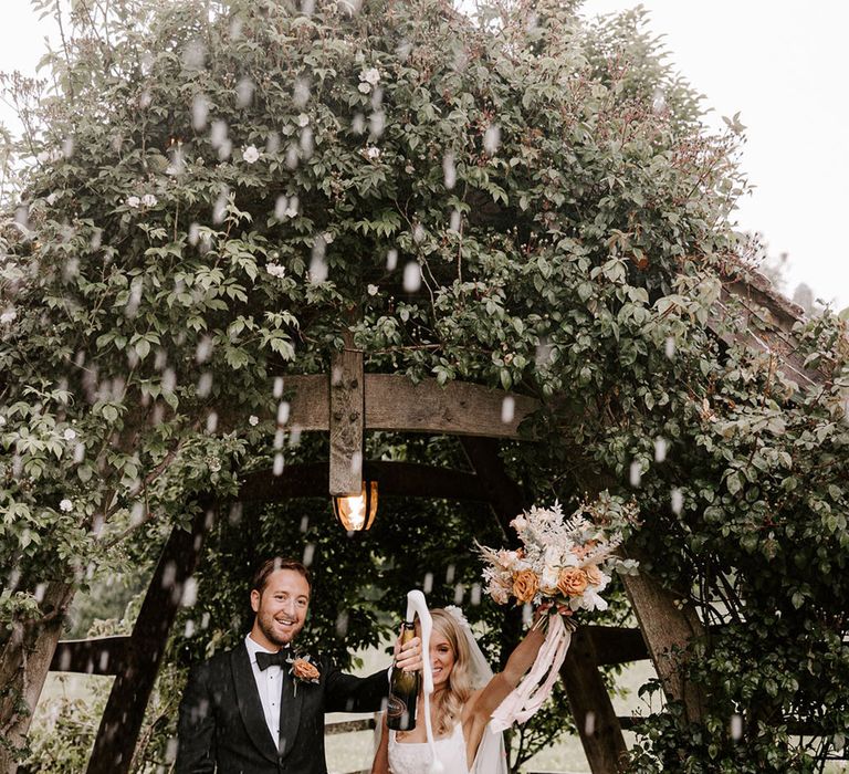 Bride and groom have a champagne popping picture as they celebrate their wedding 