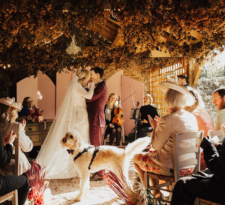 Couple share their first kiss with Dug the dog wearing a black bow tie 