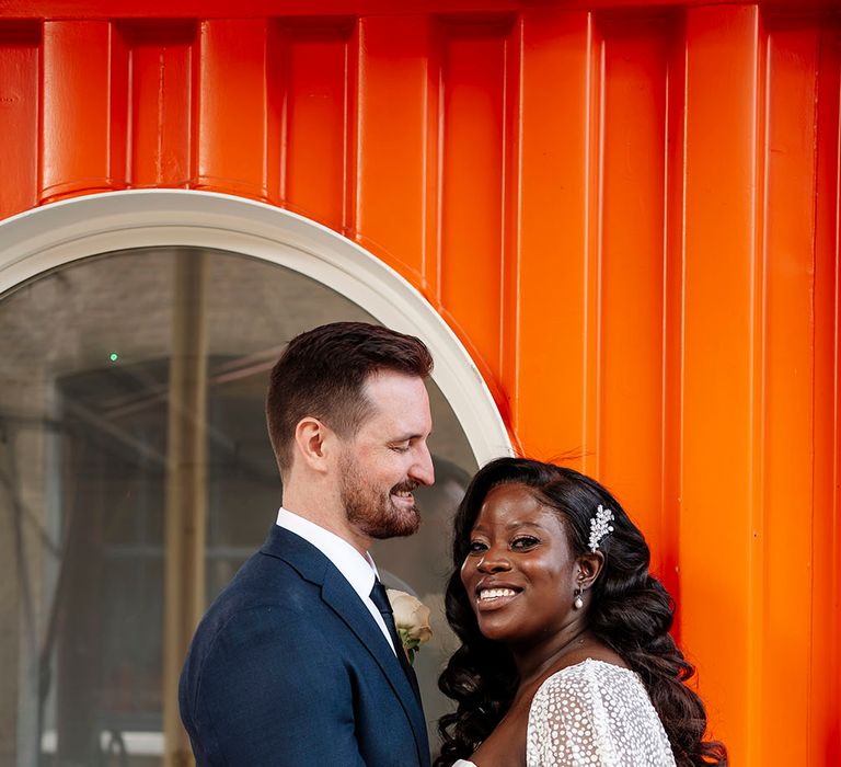 Groom looks lovingly at his bride wearing Jesus Peiro wedding cape and Suzanne Neville wedding dress 