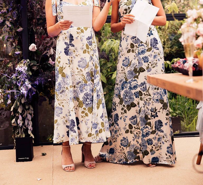 Two bridesmaids in blue and white floral dresses read out their speeches for the wedding reception 