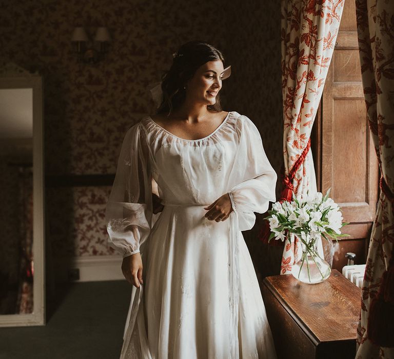 Bride in a classic strapless fitted wedding dress with a sheer balloon sleeve overlay