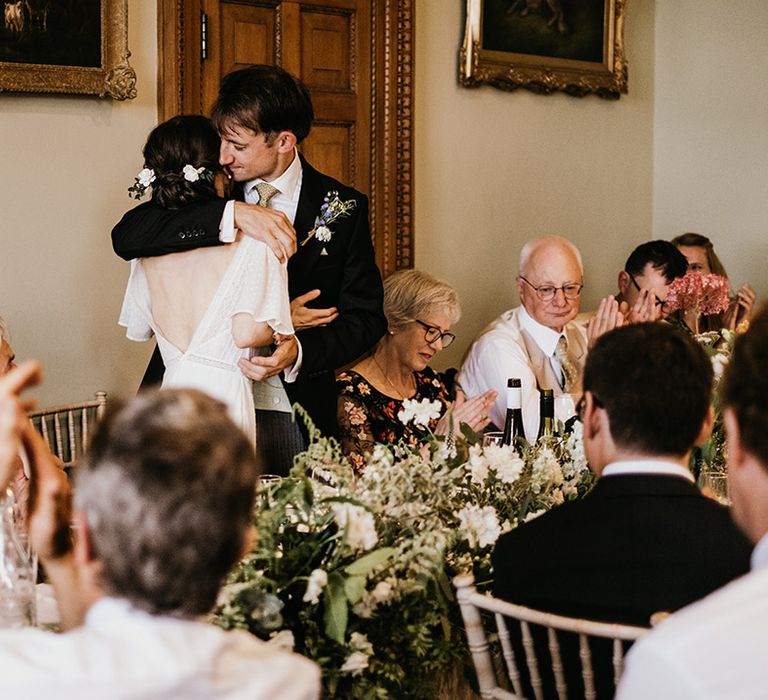 Bride and groom embracing whilst giving wedding speeches at Kelmarsh Hall