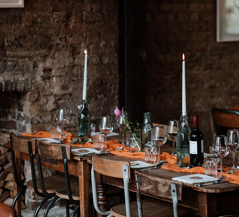 Wooden rustic tables complete with burnt orange table runners and white candles