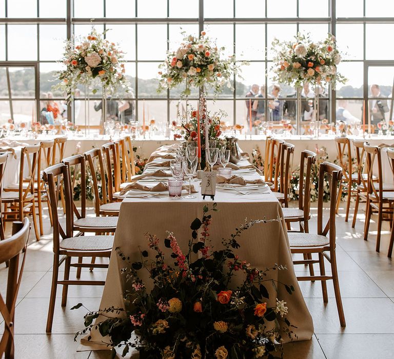 Botley Hill Barn wedding reception complete with striking floral installations to top table with pops of orange and green foliage