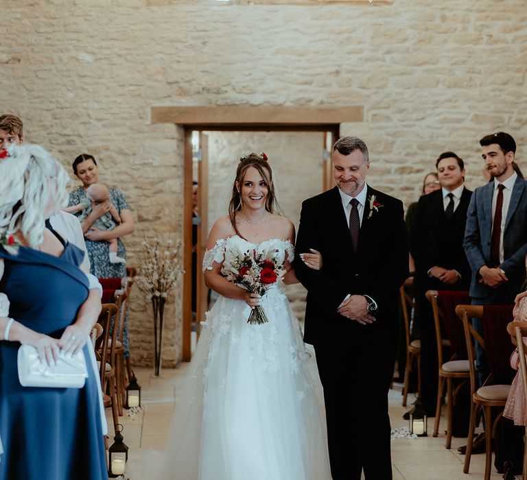 Father of the bride in a navy suit with bride in off the shoulder flower wedding dress holding bunny grass, red rose and white flower bouquet 