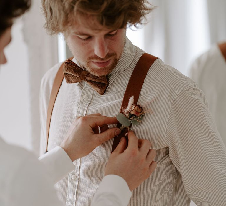 Groom in blue and white striped shirt with brown bow tie and waistcoat 