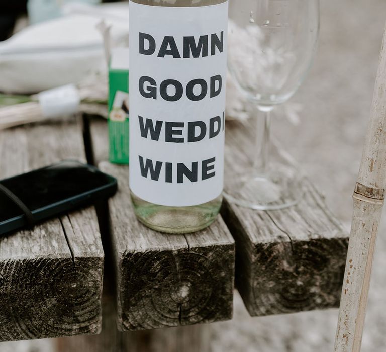 Bottle of white wine covered with white paper reading ' Damn good wedding wine' 