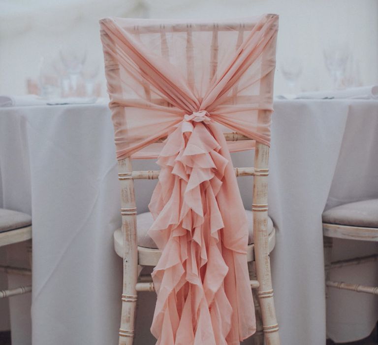 Pink ruffle wedding chair sash draped on a white wooden chair for the wedding decor 