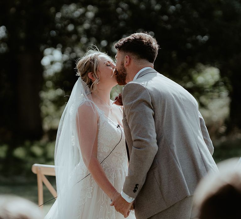 Bride & groom kiss during tipi festival wedding ceremony outdoors at The Apple Orchard 