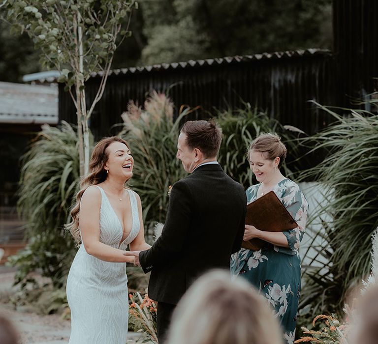 Bride in sequin Made With Love wedding dress smiling as she stands at the altar with the groom for their outdoor humanist and handfasting ceremony 