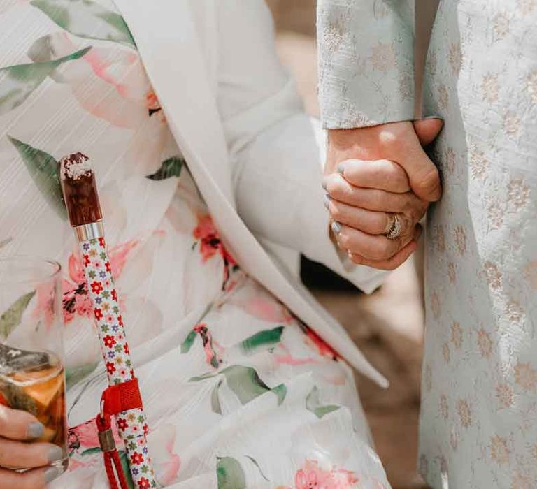 Groom in mint green sherwani holding hands with wedding guest white dress with green and pink floral details 