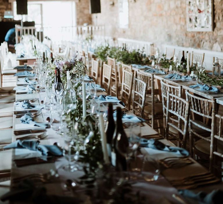 Reception room at The Barn at Harburn with suspended fairy lights, festoon lighting, foliage table runners, tapered candles and neutral table cloth 