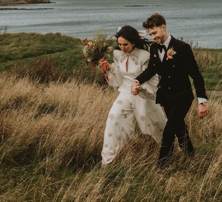 Groom in double breasted black velvet suit with the bride in Bowen Dryden sparkly jumpsuit 