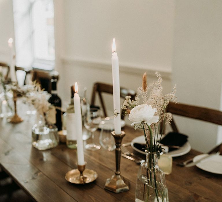 Simple and minimal wedding table decorations with bud vases full of white flowers and taper candles 