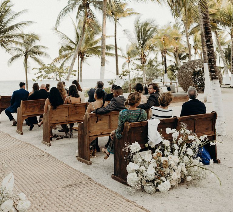 blue venado beach wedding in Mexico with outdoor ceremony with wooden church pews and palm trees 