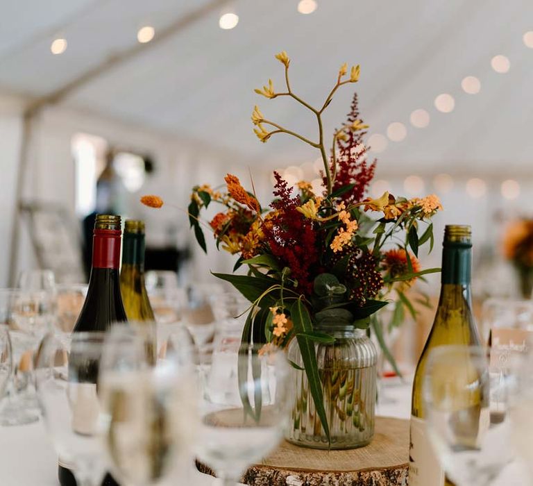 Dried orange and yellow flower and foliage wedding centrepieces on wooden tree trump circles at Broadfield Court