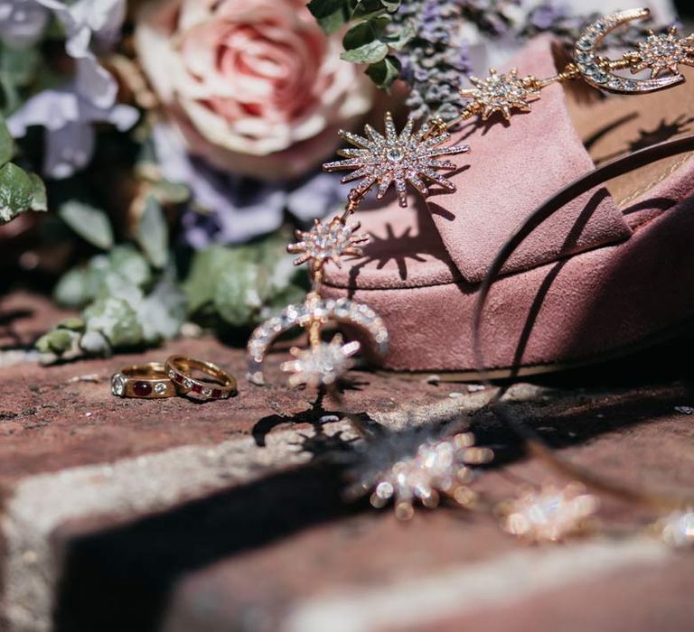 Gold and sparkly celestial bridal headband next to dusky pink wedding heels and gold wedding rings