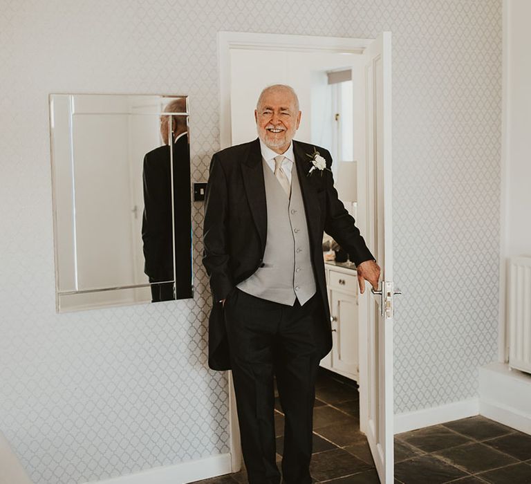 Father of the bride in black and grey wedding suit getting his first look at the bride in her wedding dress 