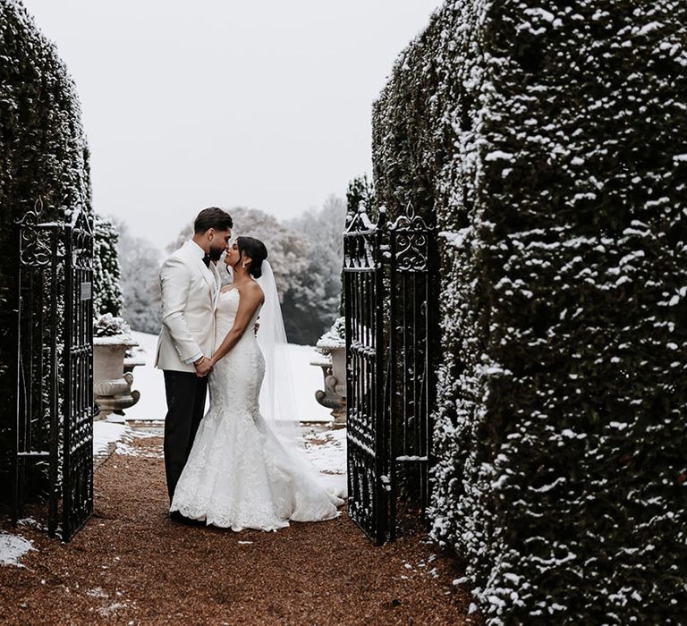 Snowy winter wedding at Hedsor House with the bride and groom wearing white wedding outfits 