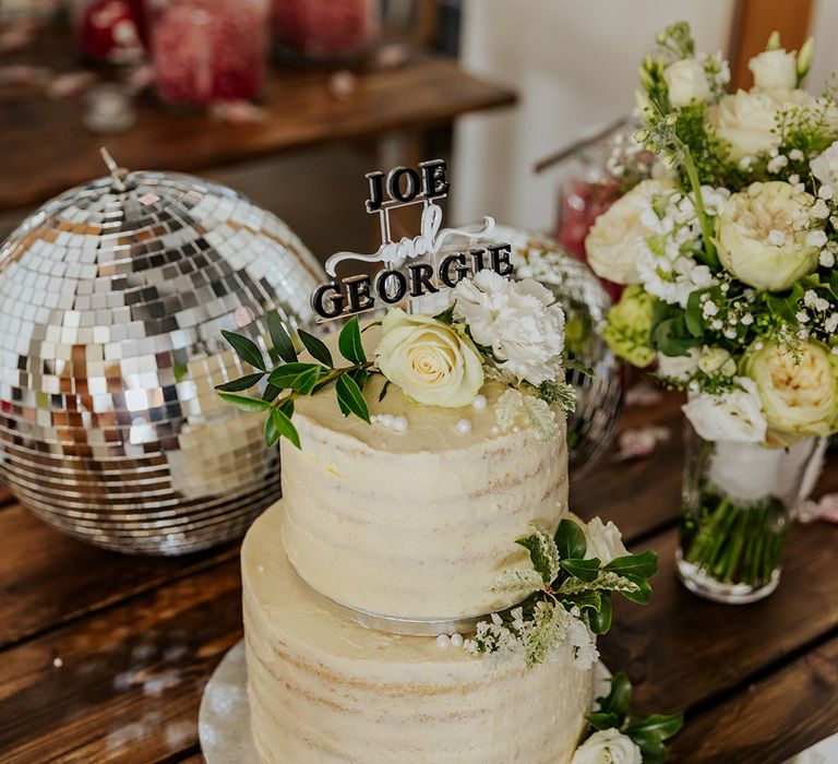 Two tier white iced wedding cake with personalised cake topper, disco balls and more 