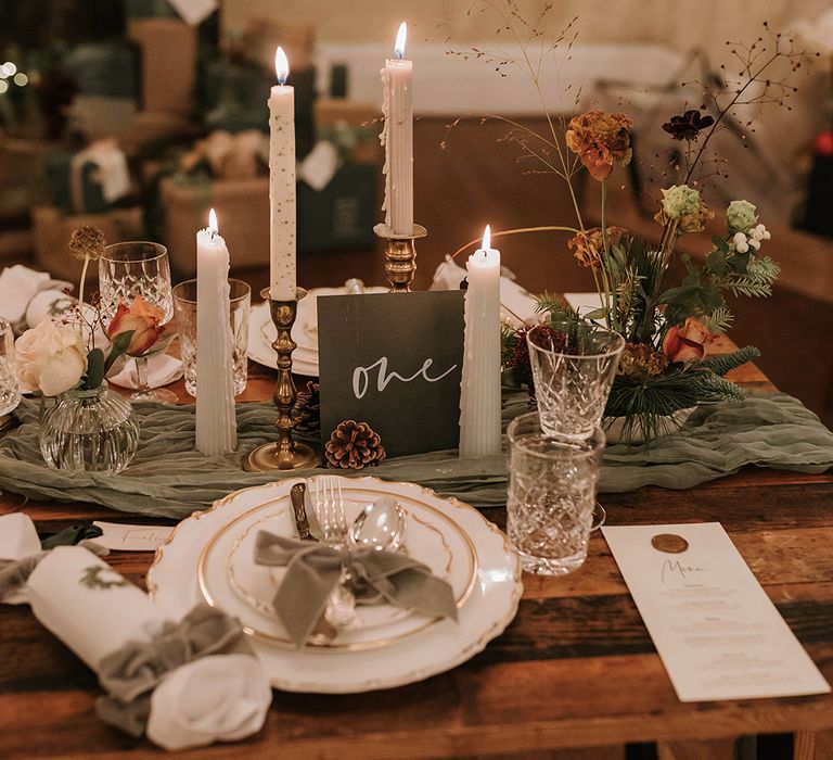 Festive Christmas table decorations with green wedding decorations, table runner, christmas crackers, and table number sign 