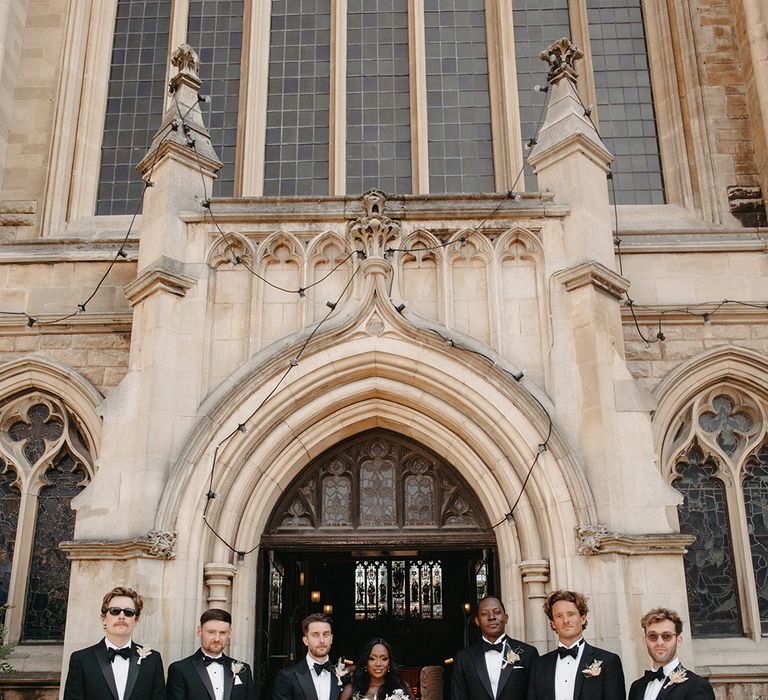 Bride and groom pose with all the groomsmen in their black tuxedos 