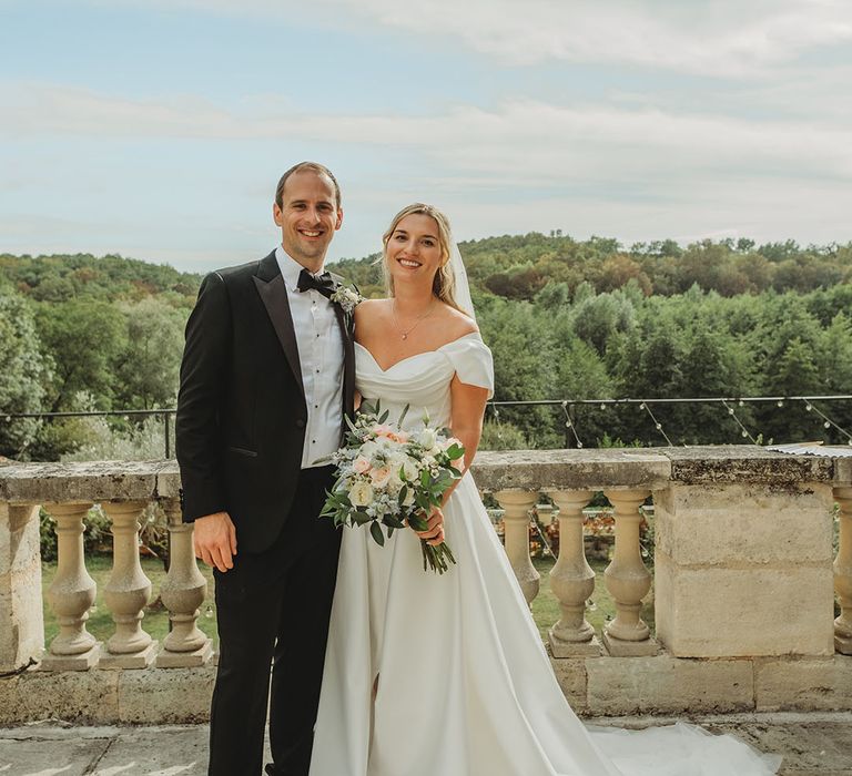 Bride in off the shoulder wedding dress posing with the groom for their couple portraits 