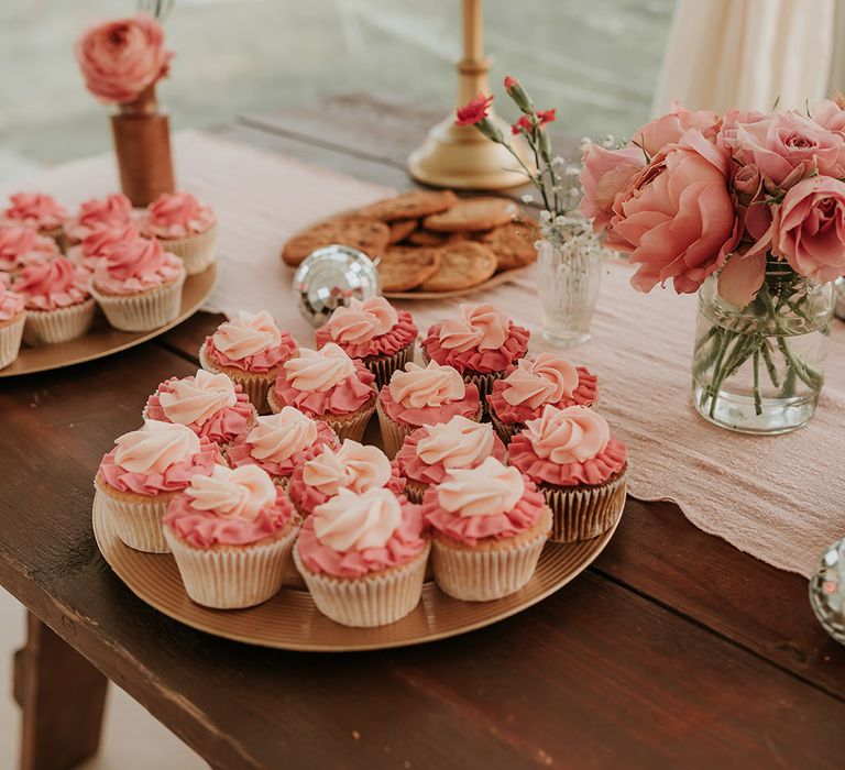 Cupcakes with pink icing on wedding dessert table 