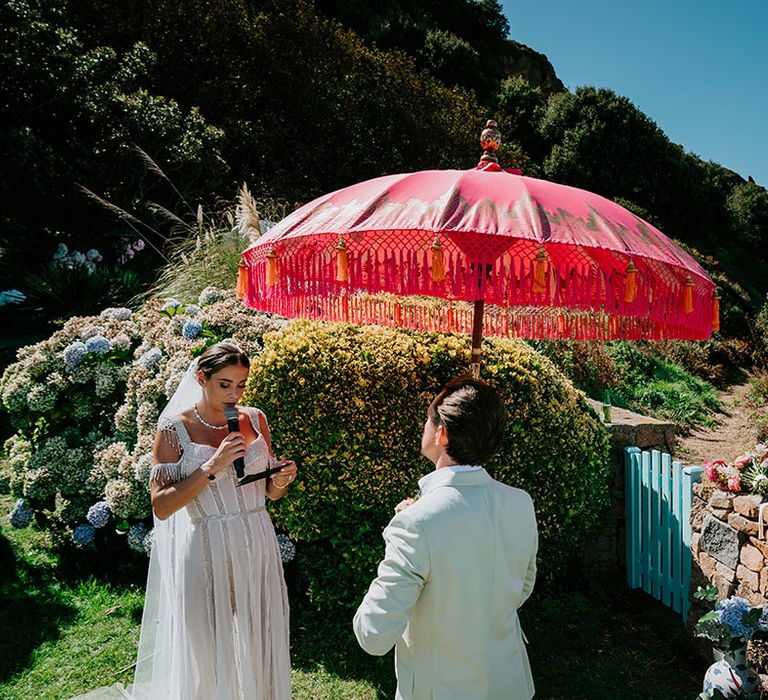 The bride and groom exchange wedding vows under the umbrella in Jersey for at home wedding 