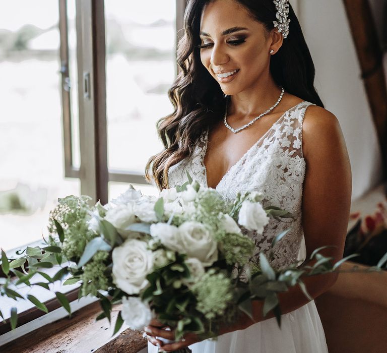 Bride carrying white rose wedding bouquet with hair in side swept syle wearing sparkly hair accessory 