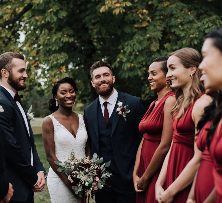 Bride and groom with their wedding party in navy suits and burgundy dresses 