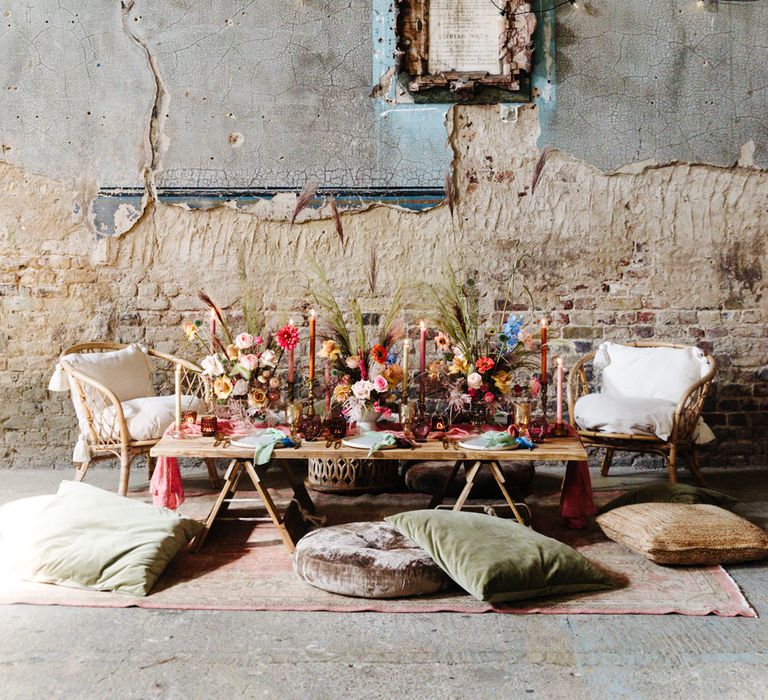 Intimate seating area at an industrial wedding with bright flowers, cushions and rugs