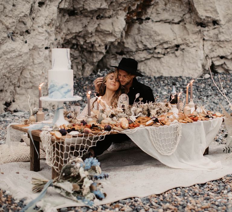 Bride and groom sitting at a grazing table at their coastal elopement 