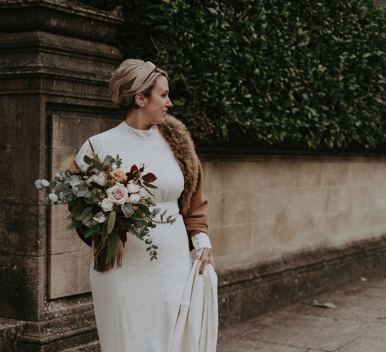 Stylish bride in Ghost wedding dress and faux fur jacket 