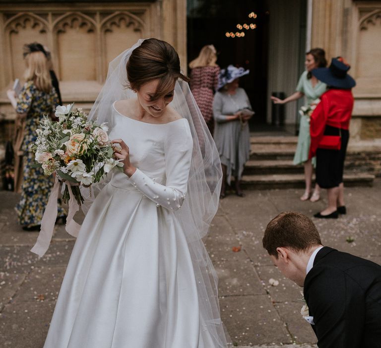 Groom helping his new bride with her wedding dress chain 