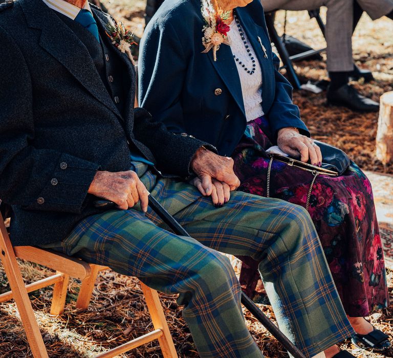 Wedding guests hold hands during woodland wedding ceremony