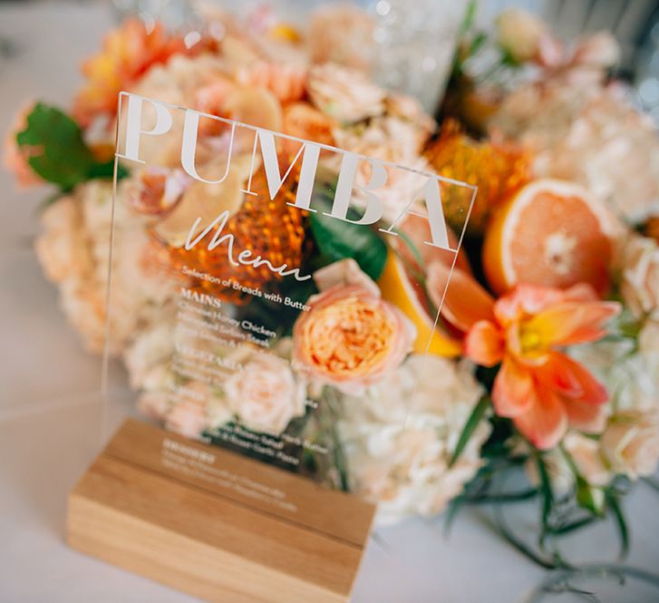 Acrylic Disney themed table menu with peach wedding flowers in the background 