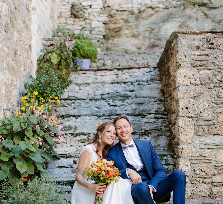 The bride and groom sitting on steps at Valeni Boutique Hotel in Greece