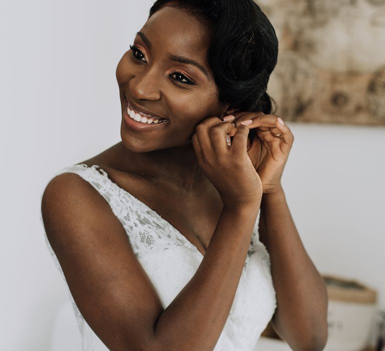 A black bride puts an earring in as she gets ready for her wedding,