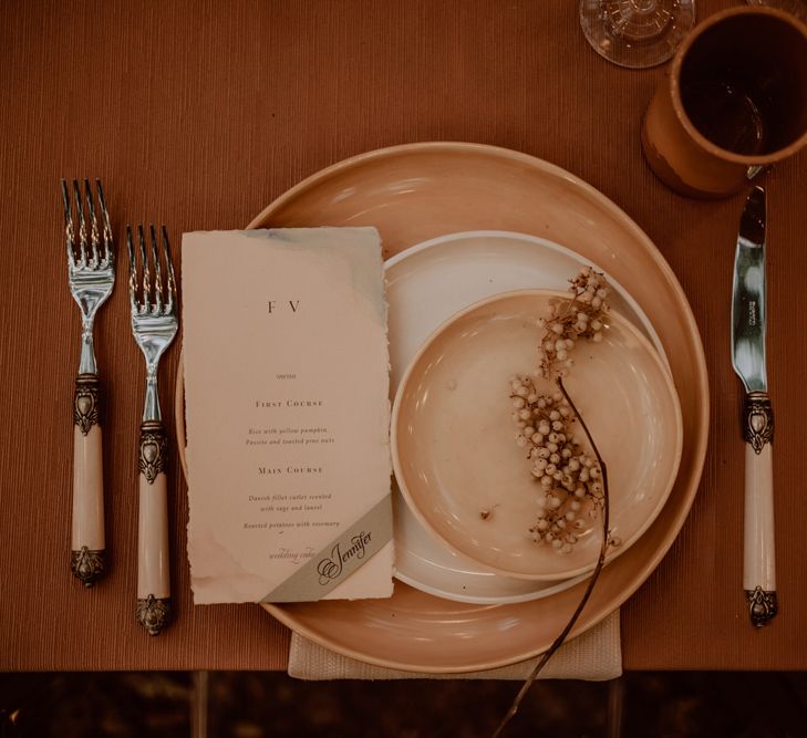 Place setting with charger plate, ivory cutlery, menu card and dried flower decor 