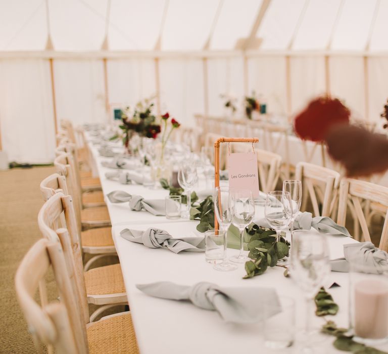 Banquet table featuring white linen table cloth and green foliage runner