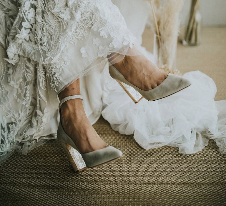 Bride in a lace and appliqué wedding dress wearing mother of pearl block heel wedding shoes 